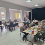 dzieci wraz z seniorami przyklejają liście