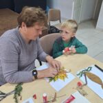 dzieci wraz z seniorami przyklejają liście