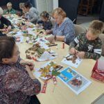 dzieci wraz z seniorami przyklejają liście