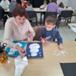 dzieci i seniorzy wyklejają bałwanki