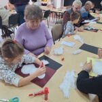 dzieci i seniorzy wyklejają bałwanki