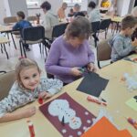 dzieci i seniorzy wyklejają bałwanki