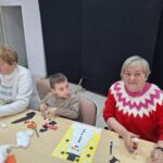 dzieci i seniorzy wyklejają bałwanki