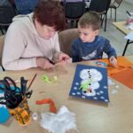 dzieci i seniorzy wyklejają bałwanki