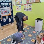 Pan policjant prezentuje z dzieckiem bezpieczną pozycję