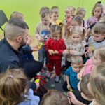 Pan policjant przekazuje przedszkolakom odblaski
