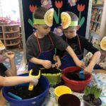 Chłopcy przygotowują doniczkę z ziemią do przesadzenia cebulek