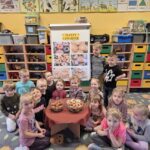 Dzieci przy tablicy demonstracyjnej z pączkami