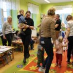 Dzieci z rodzicami poruszaja sie w kole do piosenki