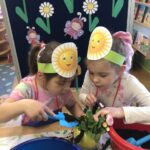 Dziewczynki dosypują ziemię do doniczki