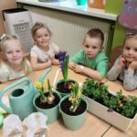 Przedszkolaki z oddziału Żuczki przy stole z zasadzonymi kwiatkami