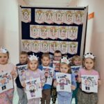 dzieci-stoja-z-pracami-plastycznymi-przed-tablica-tematyczna