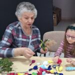 dzieci wraz z seniorami wykonują wielkanocne palmy