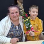 dzieci wraz z seniorami wykonują wielkanocne palmy