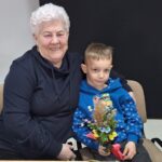 dzieci wraz z seniorami wykonują wielkanocne palmy