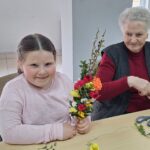 dzieci wraz z seniorami wykonują wielkanocne palmy