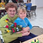 dzieci wraz z seniorami wykonują wielkanocne palmy