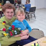 dzieci wraz z seniorami wykonują wielkanocne palmy