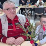 dzieci wraz z seniorami wykonują wielkanocne palmy