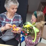 dzieci wraz z seniorami wykonują wielkanocne palmy