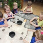 Dzieci z oddziału Żuczki zwijają glinę w rulon