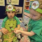 Dziewczynka karmi żółwia listkiem