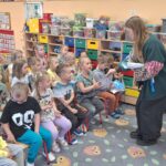 Prowadząca warsztaty wręcza dzieciom książeczki