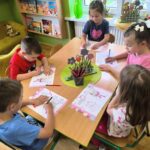 Dzieci z grupy motylki kolorują ulotki