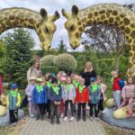 Dzieci z oddziału Biedronek przy figurach żyraf