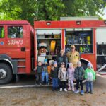 Nauczycielka z dziecmi przy wozie strażackim