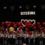 Przedszkolaki stoja na scenie z balonami