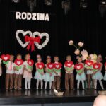 Wszystkie dzieci z serduszkowymi kwiatkami śpiewają dla rodziców