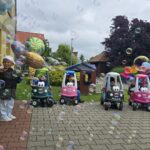 Dzieci z oddziału Krasnoludki bawią się przed przedszkolem w bańkach mydlanych