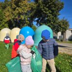 Dzieci z oddziału Krasnoludki zbierają porzucone śmieci na zielonym terenie