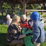 Pani z dziećmi wrzuca do foliwego worka śmieci znalezone w pobliżu przedszkola