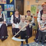 Panie pokazują dzieciom kosę i sierp