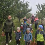 Rodzice-z-dziecmi-przechodza-przez-aleje-z-jabloniami