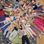 Dzieci leżą z misiami na chuście klanza