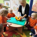 Dzieci z oddziału Żuczki obserwują jak nauczyciel przekraja dynię