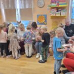 Dzieci z rodzicami nawlekają grzyby na sznurek