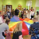 Dzieci z rodzicami poruszają sie w kole przy użyciu chusty Klanza