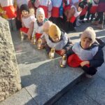 Przedszkolaki zostawiają znicze pod pomnikiem