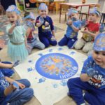 Zabawa sensoryczna farbami. Dzieci odbijają ddłonie wokół planety Ziemia