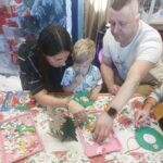 Chłopiec z rodzicami wykonuje świateczną pracę plastyczną