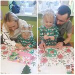 Dziewczynki z rodzicem podczas wyklejania bożonarodzeniowego więńca