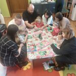 Rodziece z dziećmi przy stole podczas warsztatów bożonarodzeniowych