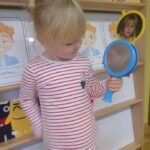 Dziewczynka z oddziału Żuczki naśladuje emocje przy użyciu lusterka