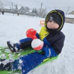 Chlopiec-na-sankach-lepi-kule-sniegowa