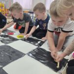 Dzieci-koloruja-czarna-farba-pola