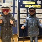 Dzieci ubrane w gogle, narciarze z kijkami